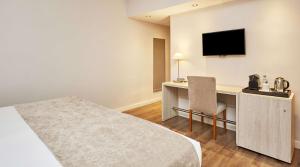 a hotel room with a bed and a desk with a television at NH Córdoba Califa in Córdoba