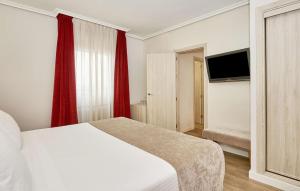 a bedroom with a white bed and red curtains at NH Córdoba Califa in Córdoba +43 photos