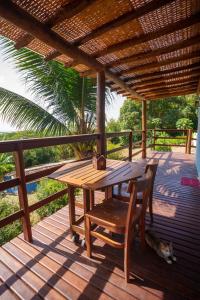 a wooden table and chair on a deck with a dog laying next to it at Casa do Ney in Fernando de Noronha +43 photos