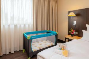 a room with a baby crib in a hotel room at NH Stuttgart Airport in Filderstadt