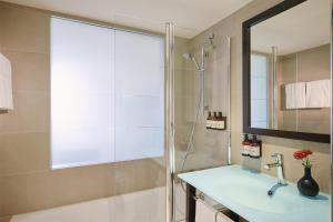 a bathroom with a shower and a sink and a mirror at NH Stuttgart Airport in Filderstadt