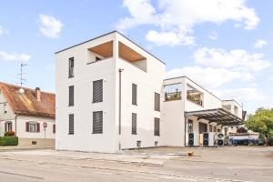 a white building with black shutters on a street at Einzimmer Wohlfühlapartment DREI klimatisiert in Friedrichshafen