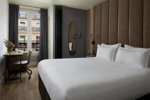 a bedroom with a large white bed and a desk at NH Paris Opéra Faubourg in Paris