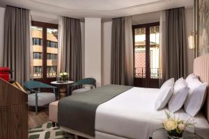a hotel room with a bed and a balcony at NH Collection Victoria in Granada