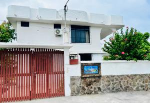 a white house with a red gate and a bush at Casa de Pablo in Puerto Ayora +5 photos