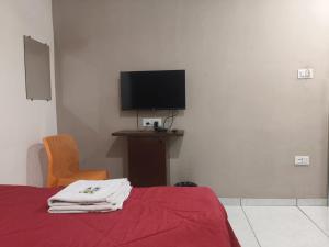 a bedroom with a bed with a tv and a chair at HOTEL OM VADODARa in Vadodara