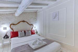 a white bedroom with a large bed with red pillows at Olive Garden Loft Relax among Olive Trees and Gazebos in Florence