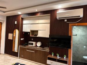 um quarto com uma cozinha com um micro-ondas e uma televisão em Bell Rooms em Noida mais 14 fotografias