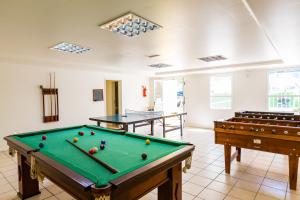a pool table in a room with two tables at Hotel Vila do Farol in Bombinhas