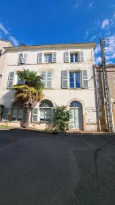 a white building with a palm tree in front of it at Jolie chambre en cœur de ville in Thouars