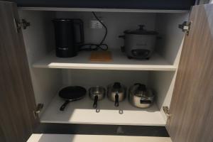 d'un placard avec une cafetière, des casseroles et des poêles dans l'établissement Bruné - Parañaque, à Manille
