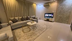 a living room with a couch and a table and a tv at شقق العارض (2) in Riyadh