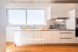 a kitchen with white cabinets and a window at The Vinehill House in Câmara de Lobos +59 photos