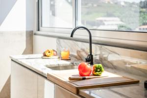 a kitchen counter with a sink with vegetables on a cutting board at The Vinehill House in Câmara de Lobos