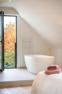 a white bathroom with a tub and a window at Vieusart in Chaumont-Gistoux