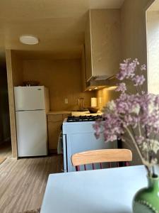 a kitchen with a white refrigerator and a table with purple flowers at Riverside Retreat in Cowichan Bay