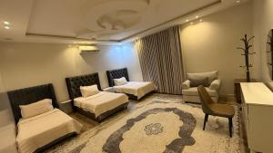 a bedroom with two beds and a couch and a chair at شقق العارض (2) in Riyadh