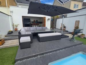 a patio with a couch and an umbrella next to a pool at Villa at 58 London Rd in Amesbury