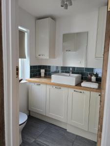 a white kitchen with a sink and a toilet at Villa at 58 London Rd in Amesbury