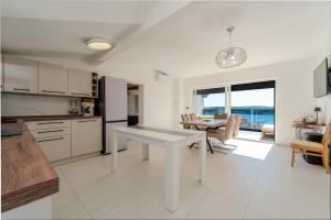 a white kitchen with a table and a dining room at Seaview Villa Summer with private pool & garden in Rtina