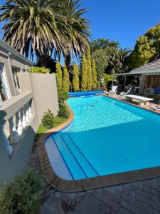 a swimming pool in a villa with palm trees at Somerset West Garden Apartments 4 in Somerset West