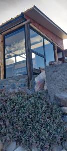 ein Gebäude mit Glasfenstern und einem Grashaufen in der Unterkunft Cabaña La Ermita, Complejo El Taller in Ciudad Lujan de Cuyo