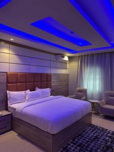 1 dormitorio con 1 cama grande y techo azul en Grand Riviera Hotel, en Port Harcourt