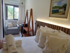 a bedroom with a bed with white pillows and a chair at Casa Californiana Pousada in Garopaba +87 photos