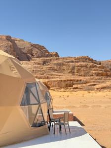 a tent with two chairs and a table in the desert at Nala Luxury Camp & Jeep Tours in Wadi Rum