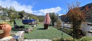 a backyard with a lawn with an umbrella and a fence at Alpujarra Casa Fortuna in Mecina Fondales