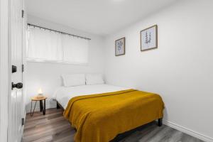a white bedroom with a bed with a yellow blanket at Charming 2BR Near Niagara College in Welland