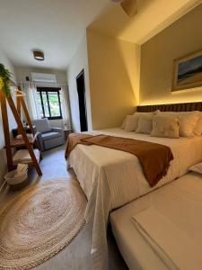 a bedroom with a large bed and a chair at Pousada Casa Californiana - Garopaba in Garopaba +114 photos