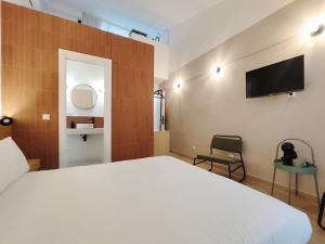 a bedroom with a bed and a tv on the wall at Mazi Plaça Gran in Mataró