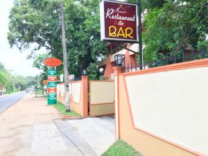 un letrero de restaurante y bar al lado de una calle en Anon Rest, en Dambulla