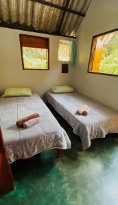 two beds in a room with green floors and windows at Chalé Único in Alto Paraíso de Goiás