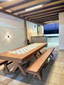 ein Holztisch und Bänke auf einer Terrasse in der Unterkunft Refúgio do Mel - Piscina e Forno a Lenha in Gravatá