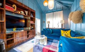 Una sala de estar con un sofá azul y un televisor. en Deluxe 5BR Villa Overlooking Golf, en El Caletón