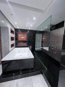 a large bathroom with a bath tub and glass walls at Villa piscine in Temara +24 photos