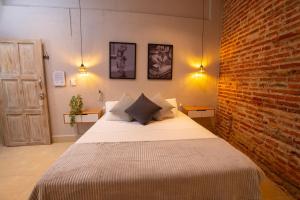 une chambre avec un lit et un mur de briques dans l'établissement Hotel Casa Agena, à Carthagène des Indes