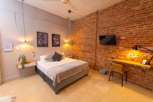 une chambre avec un lit et un mur de briques dans l'établissement Hotel Casa Agena, à Carthagène des Indes