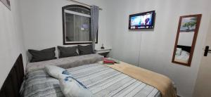 une chambre avec un lit et une télévision au mur dans l'établissement Brachil 1, à Búzios