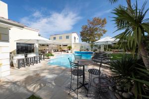 eine Terrasse mit Pool und Stühlen und Sonnenschirmen in der Unterkunft Suite Shiraz in Meadowridge