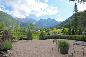 a patio with tables and chairs and mountains in the background at Mühlradl Apartments Gosau in Gosau