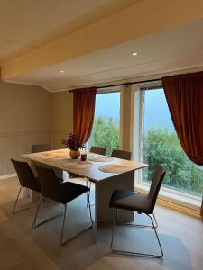 ein Esstisch mit Stühlen und ein großes Fenster in der Unterkunft Wonderful Seaview Apartment in Tromsø