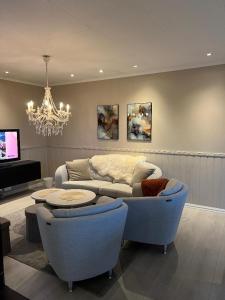 ein Wohnzimmer mit einer Couch und Stühlen und einem Kronleuchter in der Unterkunft Wonderful Seaview Apartment in Tromsø