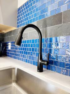 a kitchen sink with a faucet and blue tiles at The Washington Apartments in Evansville +30 photos