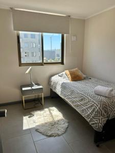 a bedroom with a bed with a lamp and a window at Departamento a Pasos de la UCM e Inacap in Talca