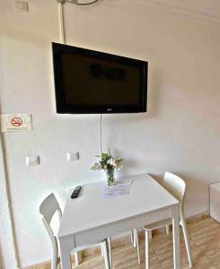 Una mesa blanca con sillas y un televisor en la pared. en Lindo estudio en Martiánez, en Puerto de la Cruz