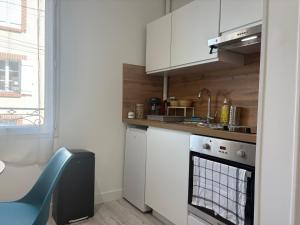 una cocina con armarios blancos y una silla azul en Bienvenue Au Margny Nest, en Margny-lès-Compiègne 8 fotos más