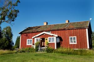 een rode schuur in een veld met een blauwe lucht bij Pensionat Hogården in Boxholm